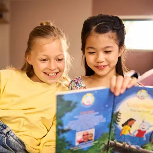 Twee meisjes kijken samen in een leesboek Twee meisjes kijken samen in een leesboek