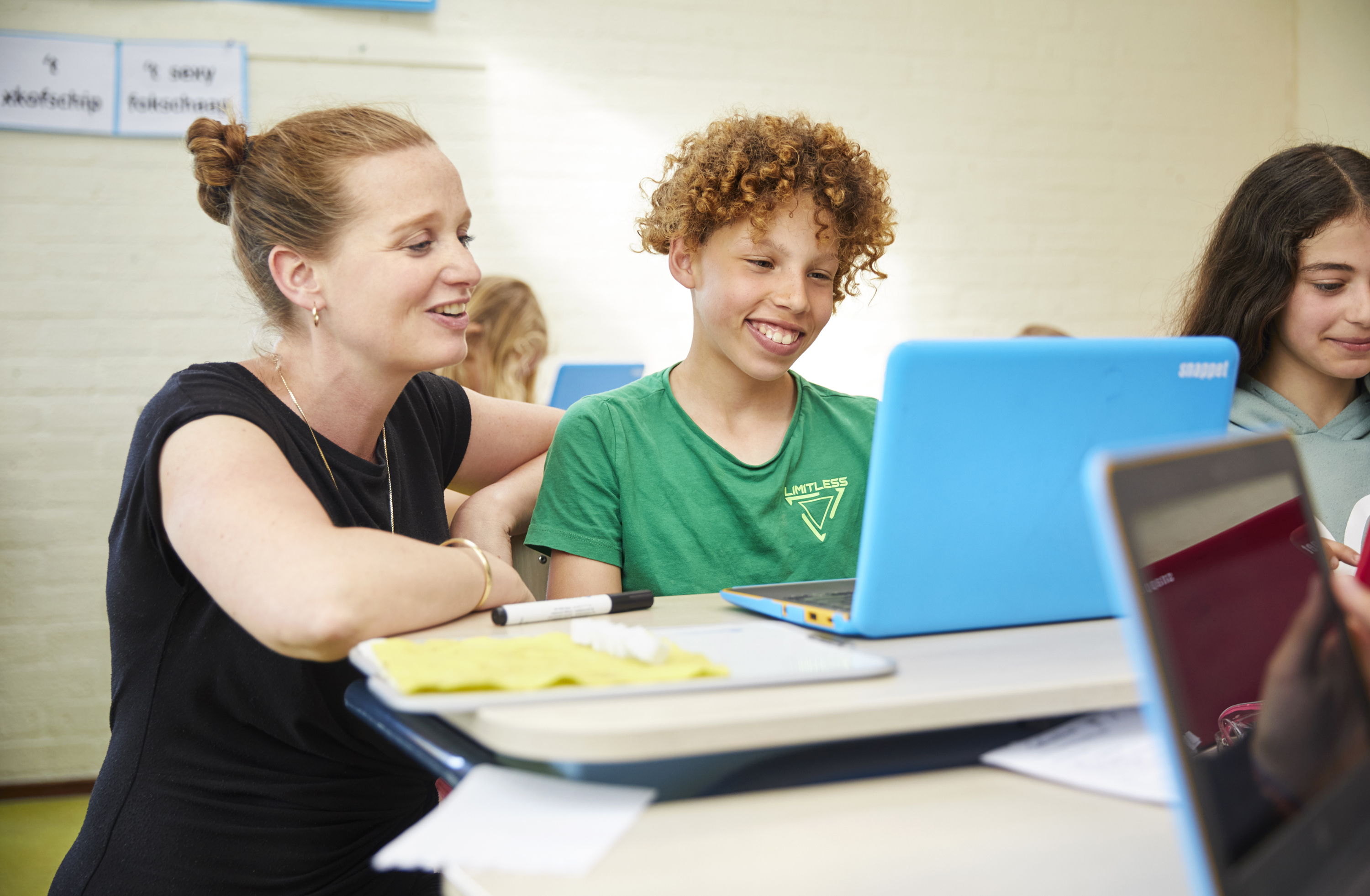 Leerkracht en leerling primair onderwijs achter laptop