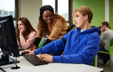 Cito volgsysteem VO - docent helpt leerling bovenbouw achter pc Cito volgsysteem VO - docent helpt leerling bovenbouw achter pc