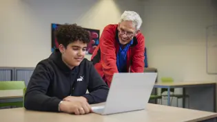 ICT-ondersteuner Tjeerd helpt een bovenbouwleerling met zijn laptop ICT-ondersteuner Tjeerd helpt een bovenbouwleerling met zijn laptop