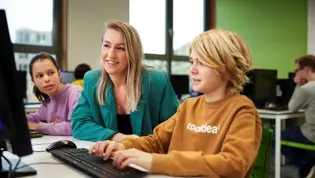 Cito volgsysteem VO - docent helpt leerling achter pc Cito volgsysteem VO - docent helpt leerling achter pc