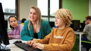 Cito volgsysteem VO - docent helpt leerling achter pc Cito volgsysteem VO - docent helpt leerling achter pc