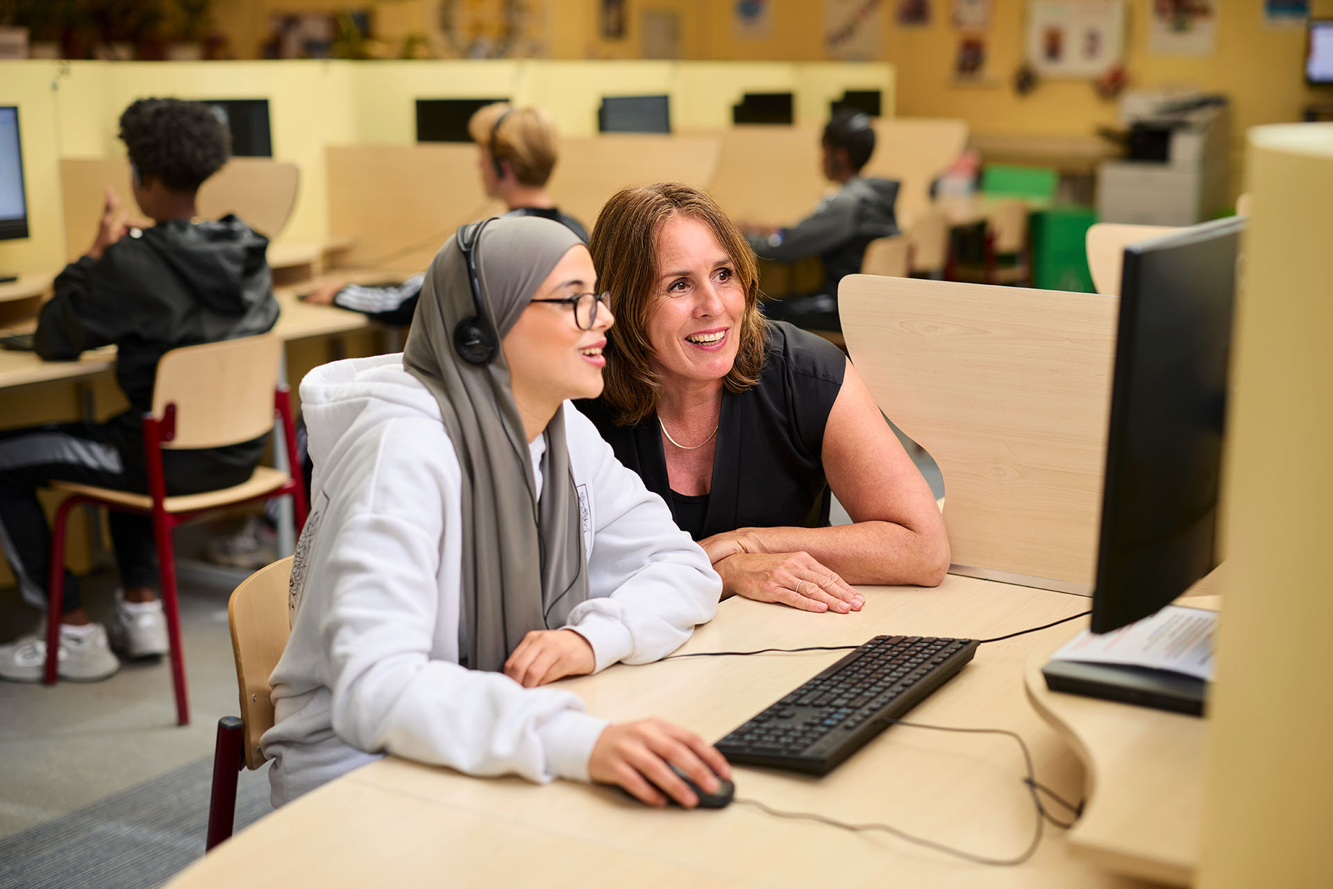 Docent kijkt mee met leerling